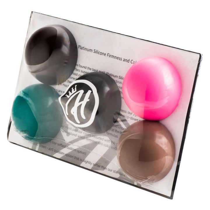 Mr. Hankey’s Toys Sample Pack in clear packaging displaying five silicone firmness samples in various colors, including Natural Tan, Metallic Green, Bubblegum Pink, Deep Brown, and Black.