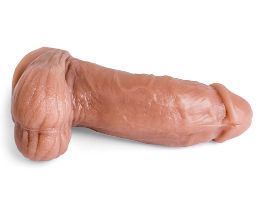 Topher Michels realistic dildo lying on its side, showcasing lifelike shaft curvature and detailed texture in natural tan silicone.