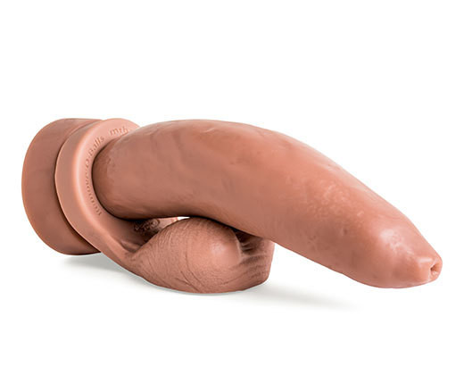 Ramrodder silicone dildo laying flat in Natural Tan with Remove-O-Balls attached, showcasing realistic uncut head and handcrafted texture.