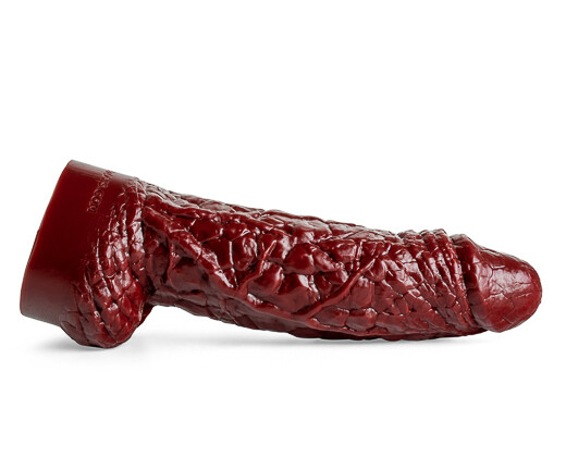 The Theeng dildo lying on its side, showcasing its rugged, rocky textures and pulled-back foreskin detail in blood red silicone.